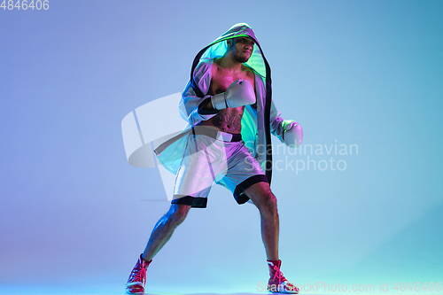 Image of High-fashion styled man in white outfit pacticing box isolted over gradient background in neon light