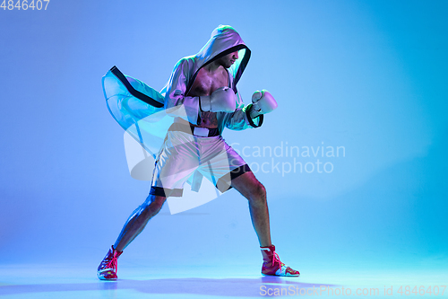 Image of High-fashion styled man in white outfit pacticing box isolted over gradient background in neon light