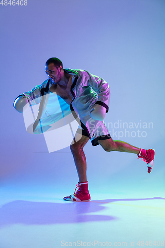 Image of High-fashion styled man in white outfit pacticing box isolted over gradient background in neon light