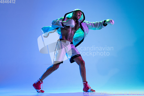 Image of High-fashion styled man in white outfit pacticing box isolted over gradient background in neon light