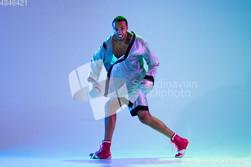 Image of High-fashion styled man in white outfit pacticing box isolted over gradient background in neon light