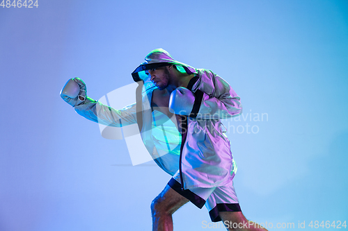 Image of High-fashion styled man in white outfit pacticing box isolted over gradient background in neon light