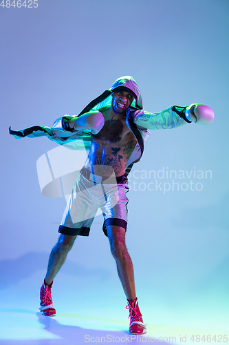 Image of High-fashion styled man in white outfit pacticing box isolted over gradient background in neon light