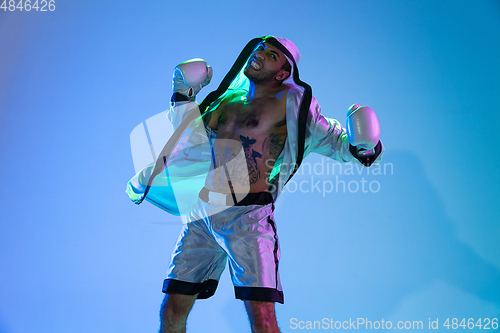 Image of High-fashion styled man in white outfit pacticing box isolted over gradient background in neon light