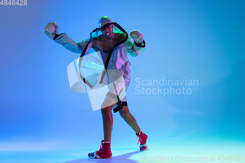 Image of High-fashion styled man in white outfit pacticing box isolted over gradient background in neon light