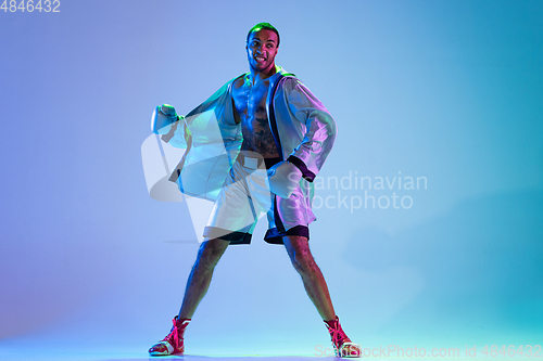 Image of High-fashion styled man in white outfit pacticing box isolted over gradient background in neon light