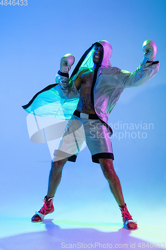 Image of High-fashion styled man in white outfit pacticing box isolted over gradient background in neon light