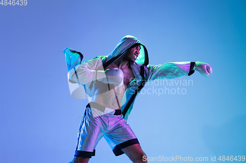 Image of High-fashion styled man in white outfit pacticing box isolted over gradient background in neon light