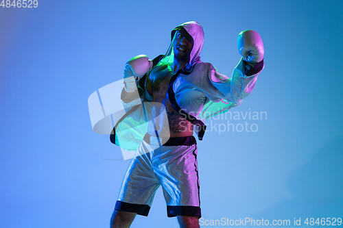 Image of High-fashion styled man in white outfit pacticing box isolted over gradient background in neon light