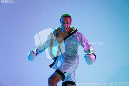 Image of High-fashion styled man in white outfit pacticing box isolted over gradient background in neon light