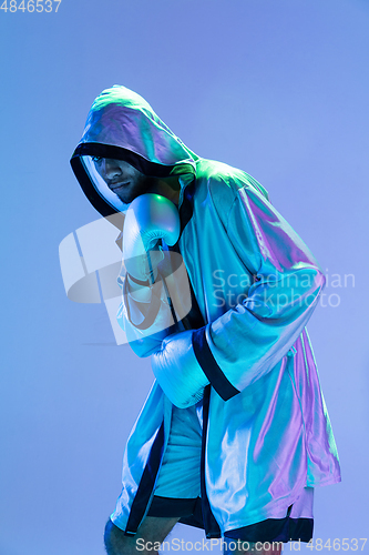 Image of High-fashion styled man in white outfit pacticing box isolted over gradient background in neon light