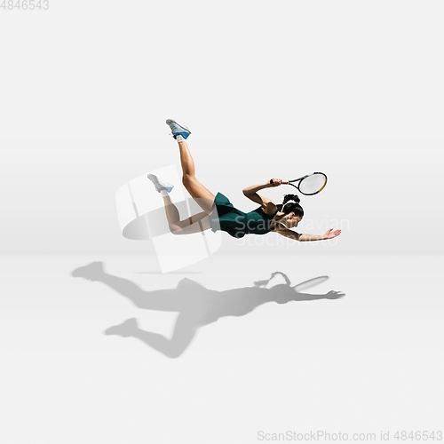 Image of Young caucasian professional sportswoman levitating, flying while playing tennis isolated on white background