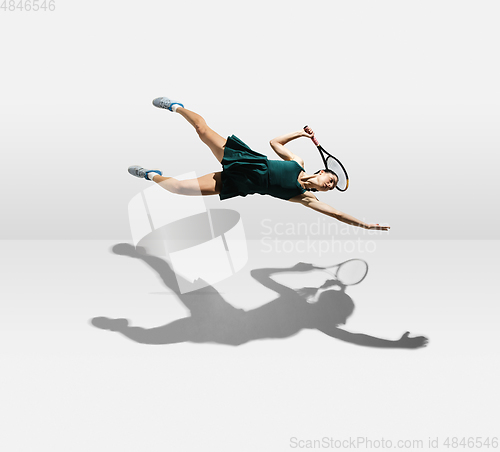 Image of Young caucasian professional sportswoman levitating, flying while playing tennis isolated on white background