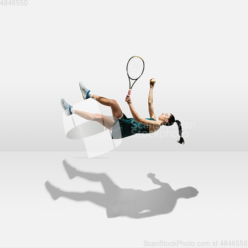 Image of Young caucasian professional sportswoman levitating, flying while playing tennis isolated on white background