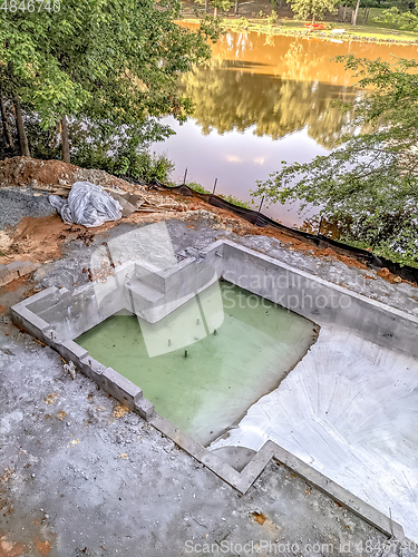 Image of large luxurious pool under construction by the lake