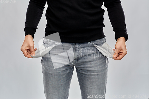 Image of close up of man showing empty pockets over grey