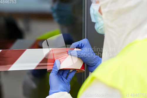 Image of healthcare worker sealing door with caution tape