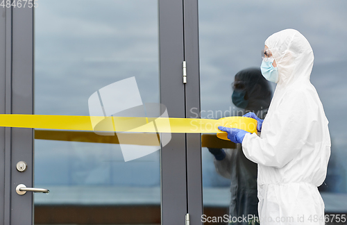 Image of healthcare worker sealing door with caution tape