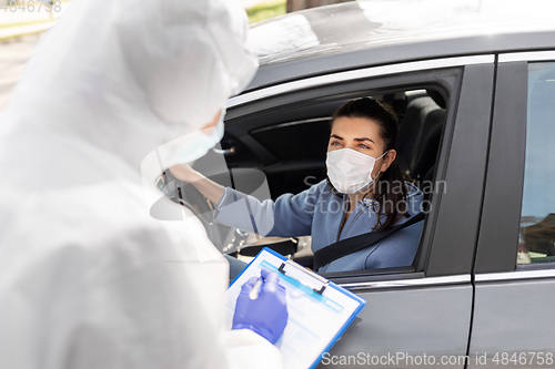 Image of healthcare worker with clipboard and woman in car