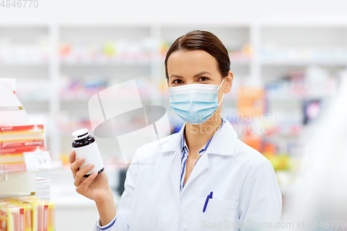 Image of female apothecary in mask with drug at pharmacy