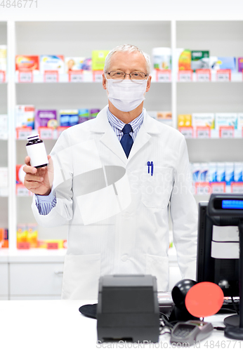 Image of senior apothecary in mask with drug at pharmacy