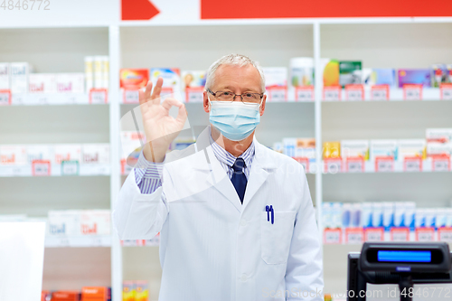 Image of senior apothecary in mask at pharmacy showing ok