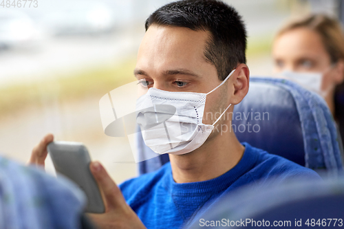 Image of man in mask using smartphone in travel bus