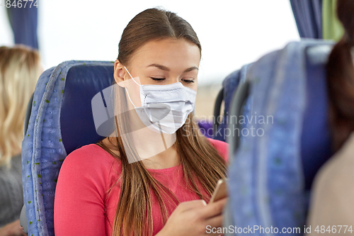 Image of woman in mask using smartphone in travel bus