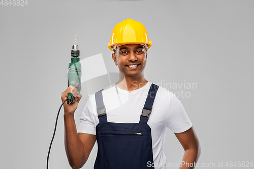 Image of happy indian builder in helmet with electric drill