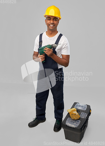 Image of happy indian builder in helmet with electric drill