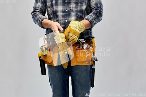 Image of builder with working tools putting gloves on