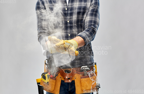 Image of builder with working tools and gloves using talc