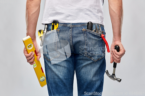 Image of man with level and working tools in pockets