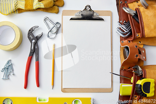 Image of clipboard with white paper, pencil and work tools