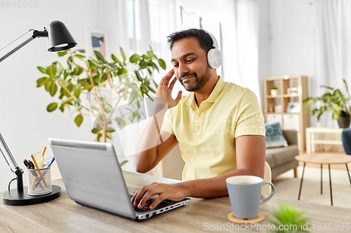 Image of man in headphones with laptop working at home