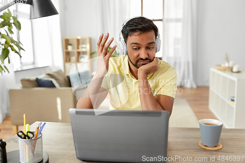 Image of man in headphones with laptop working at home