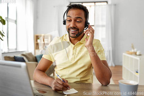 Image of indian man with headset and laptop working at home