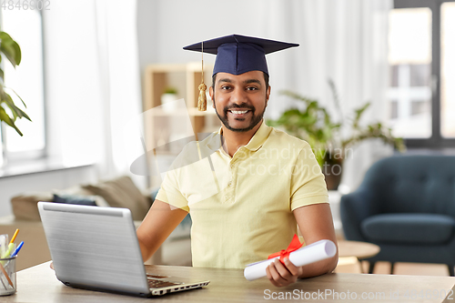 Image of indian student with laptop and diploma at home