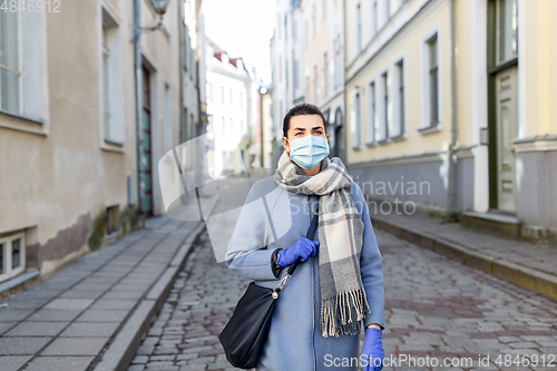 Image of woman wearing medical mask and gloves in city