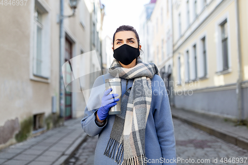 Image of woman in reusable mask with tumbler in city