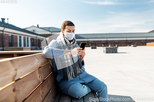 Image of woman in face mask with smartphone in city