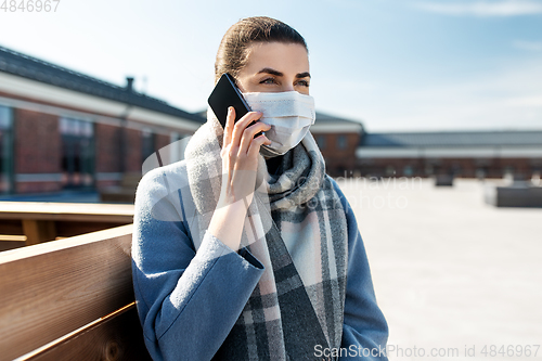 Image of woman in face mask calling on smartphone in city