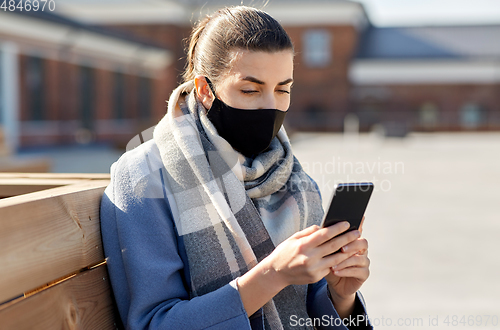 Image of woman in face mask with smartphone in city