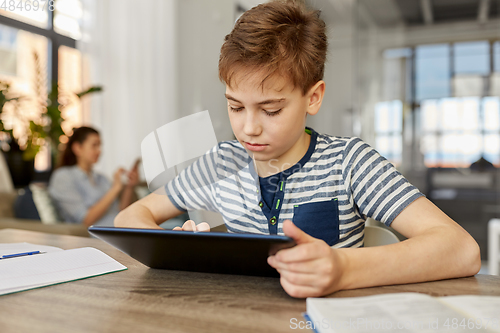 Image of student boy with tablet computer learning at home