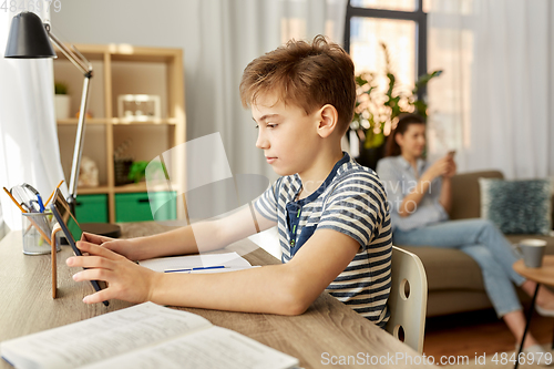 Image of student boy with tablet computer learning at home