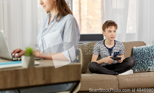 Image of boy with gamepad playing video game at home