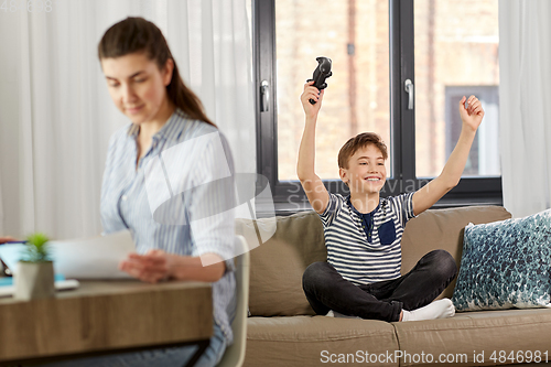 Image of happy boy with gamepad playing video game at home