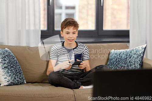 Image of boy with gamepad playing video game at home