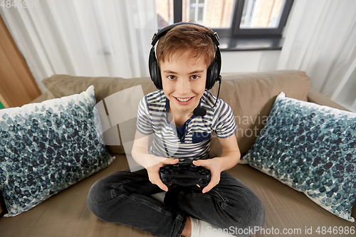 Image of boy with gamepad playing video game at home