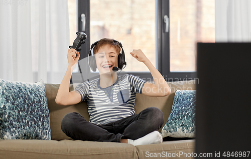 Image of boy with gamepad playing video game at home